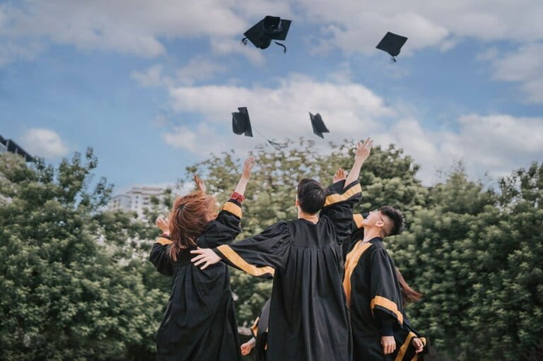 Asian students excitedly throw mortarboard into the air according to graduation day tradition Asian students excitedly throw mortarboard into the air according to graduation day tradition