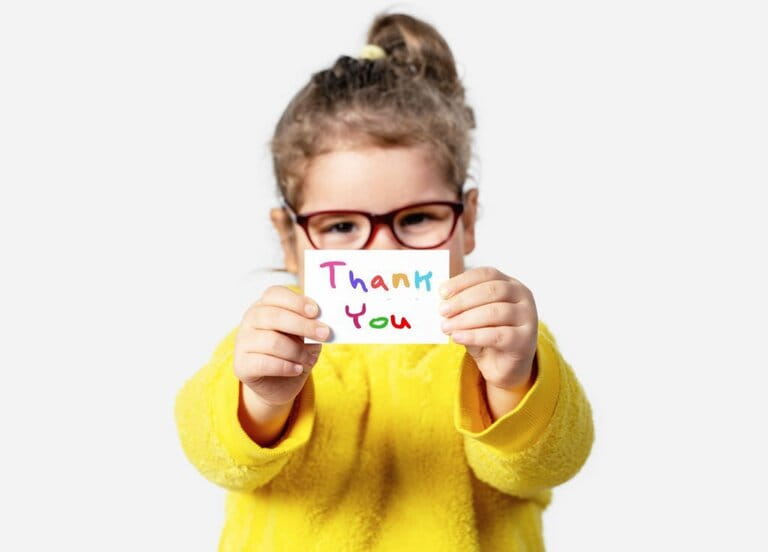 Adorable little girl holding a piece of paper with a Thank you note. Adorable little girl holding a piece of paper with a Thank you note.