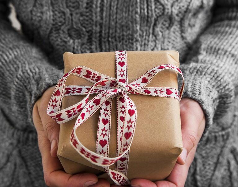 female hand holding a hand-wrapped gift box female hand holding a hand-wrapped gift box