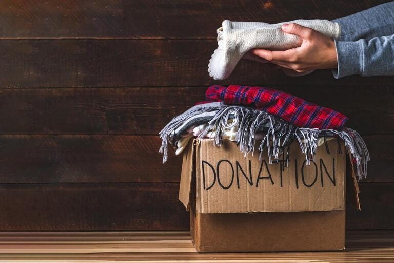 Donation concept. Donation box with donated clothes on wooden background. Charity. Help the poor and needy. Donation concept. Donation box with donated clothes on wooden background. Charity. Help the poor and needy.