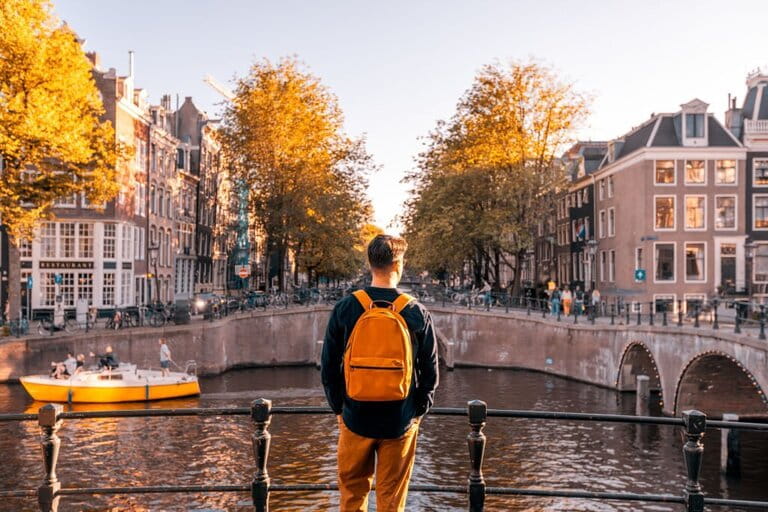 Rear view of a man looking at Amsterdam canal on a sunny day, Netherlands  Rear view of a man looking at Amsterdam canal on a sunny day, Netherlands